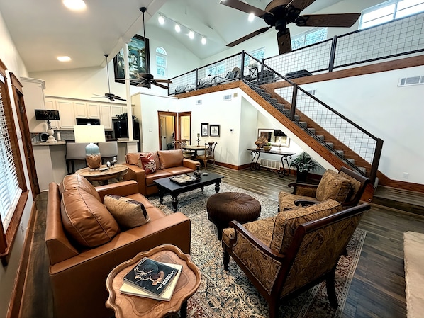 A spacious living area with leather sofas, a coffee table, and a staircase leading to an upper level.