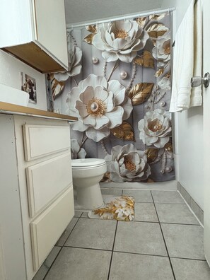 Un baño con inodoro, lavamanos y cortina de ducha con estampado floral.