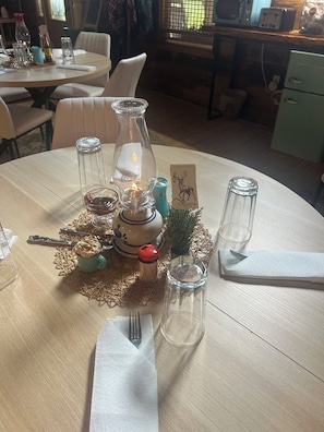 Une table mise pour le dîner, avec une bougie, un menu et une petite plante décorative.