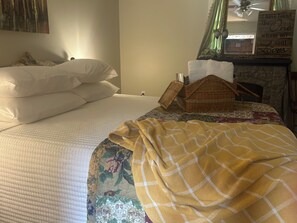 A neatly made bed with white linens, a yellow plaid blanket, and a floral-patterned bedspread.