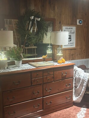 A wooden dresser with drawers, a mirror, and a sign that reads 'POLAROID Book + Shake It + Stick It + Sign It'.