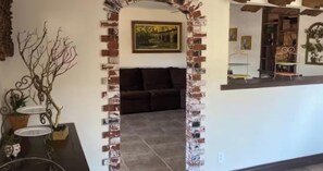 Ein Wohnbereich mit einer Couch, einer Zierpflanze und einem gerahmten Bild an der Wand.