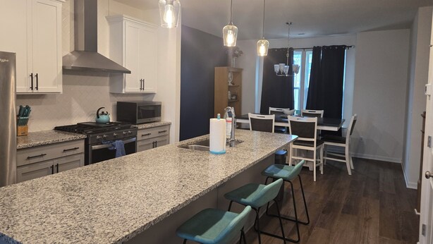 A modern kitchen with granite countertops, stainless steel appliances, and pendant lighting. - Relaxing Small Town Getaway in Bright 3B/3.5 Ba TH in Wendell (Wendell)