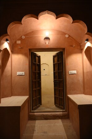 A corridor with a door leading to a room, a light fixture above the door, and a switch on the wall. - Bala Sahai Haveli Certified Heritage Stay, Mahar Kalan, Near Samod-CP (Mahar Kalan)