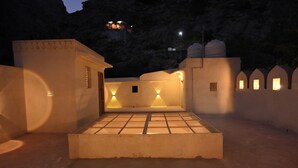 Un patio con piso de baldosas, un espacio de descanso pequeño y una pared con diseño geométrico.