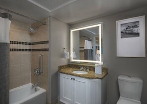 A bathroom with a bathtub, a sink with a mirror, and a toilet.