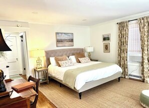 Quarto com cama, mesas de cabeceira, luminária, cadeira e porta.