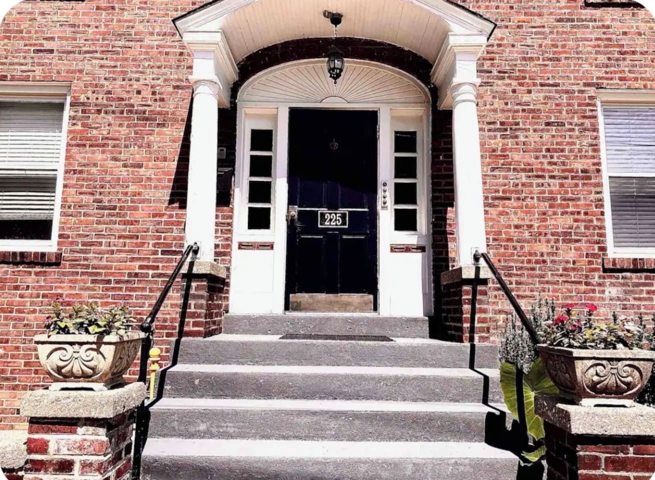 A brick building with a black door, a number '425' sign, and a set of stone steps leading to the entrance.