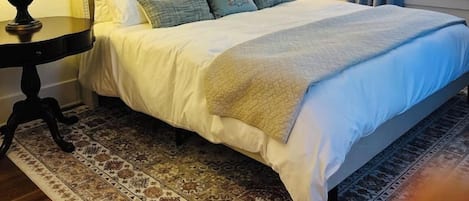 A hotel room with a large bed, two bedside lamps, a patterned rug, and a framed picture on the wall.