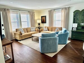 A living room with a sofa set, two armchairs, a coffee table, and a green cabinet.