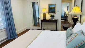 A hotel room with a large bed, two bedside lamps, a nightstand, a painting, and a mirror.