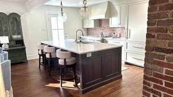A kitchen with a large island, white cabinets, and a brick accent wall.