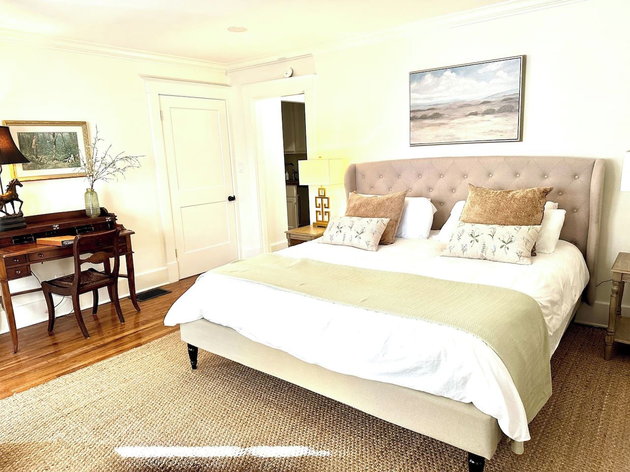 A bedroom with a large bed, a desk, and a chair.