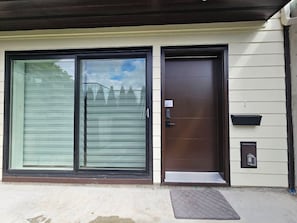 A house with a large sliding glass door and a solid front door, both with dark frames.