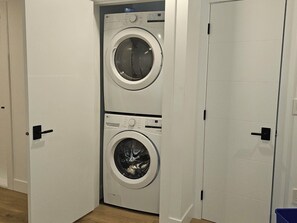Un lavadero con dos lavadoras apiladas y una puerta.