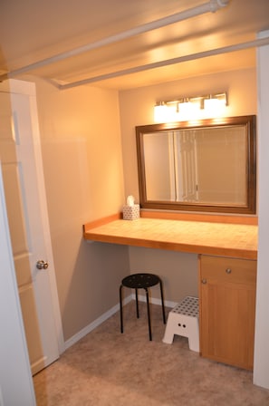 A bathroom with a vanity, a mirror, a stool, and a cabinet.