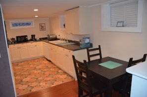A compact kitchen with white cabinets, a microwave, a toaster, and a sink.