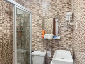 Ein Badezimmer mit Duschkabine, Toilette, Waschbecken und Spiegel mit Zierrahmen.