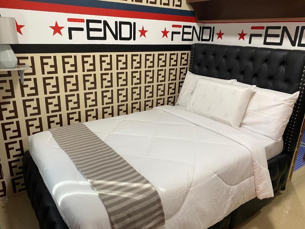 A bed with a patterned headboard, a white bedspread, and a pillow.