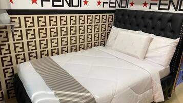 A bed with a patterned headboard, a white bedspread, and a pillow.