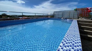 A swimming pool with a tiled edge, a metal ladder, and a sign with pool rules.