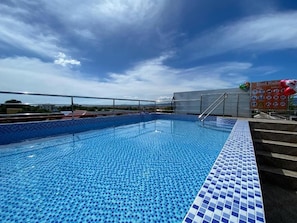 A swimming pool with a tiled edge, a metal ladder, and a sign with pool rules. - MDM HOTEL  (Cordova)