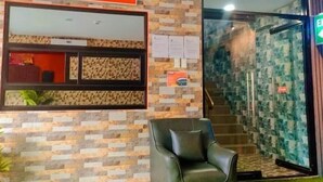 A reception area with a sign, a reception desk, a staircase, and a leather chair.