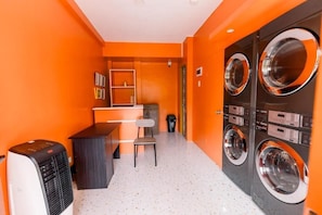 A laundry room with a chair, a small table, and a washing machine. - MDM HOTEL  (Cordova)