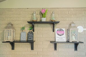 Een muur met een bakstenen patroon en drie planken met decoratieve objecten.