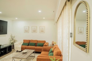 A living room with a sectional sofa, a coffee table, a television, and framed artwork on the wall. - Spacious 5 bedroom Niagara Falls retreat. Minutes to USA Canada cross border! (Niagara Falls)