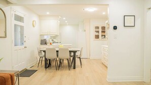 Eine moderne Küche mit weißen Schränken, einem Essbereich mit Tisch und Stühlen sowie einem kleinen Kühlschrank.