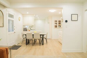 A modern kitchen with white cabinets, a dining area with a table and chairs, and a small refrigerator. - Spacious 5 bedroom Niagara Falls retreat. Minutes to USA Canada cross border! (Niagara Falls)