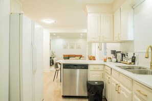 A kitchen with white cabinets, a dishwasher, a sink, and a trash bin. - Spacious 5 bedroom Niagara Falls retreat. Minutes to USA Canada cross border! (Niagara Falls)