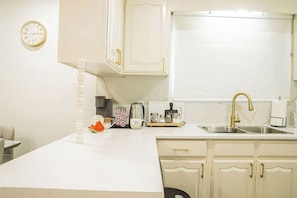 A kitchen with white cabinets, a stainless steel sink, and a clock on the wall. - Spacious 5 bedroom Niagara Falls retreat. Minutes to USA Canada cross border! (Niagara Falls)