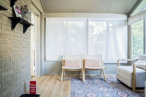 A room with a brick wall, two wicker chairs, a patterned rug, and a large window with a view of trees. - Spacious 5 bedroom Niagara Falls retreat. Minutes to USA Canada cross border! (Niagara Falls)