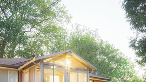 Ein kleines, eingeschossiges Haus mit einer überdachten Veranda, einem Tisch und Stühlen sowie einem kleinen Garten.