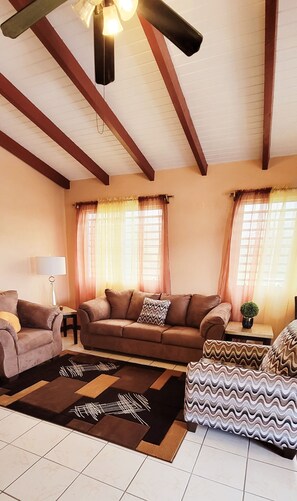 A living room with a sofa, armchairs, a coffee table, and a ceiling fan. - 2-BR apt in beautiful St Thomas filled with local flava (Charlotte Amalie)
