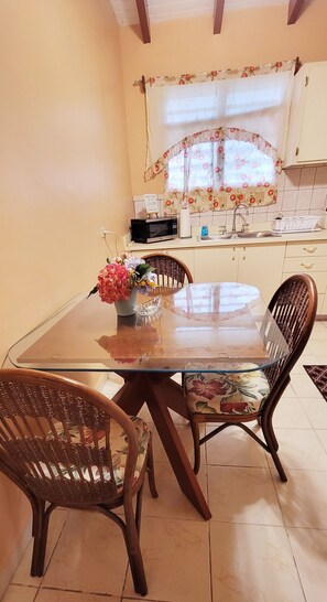 A dining area with a glass-top table, wicker chairs, and a floral vase. - 2-BR apt in beautiful St Thomas filled with local flava (Charlotte Amalie)