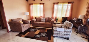 Un salon avec un canapé, un fauteuil et une petite table sur laquelle se trouve une lampe.