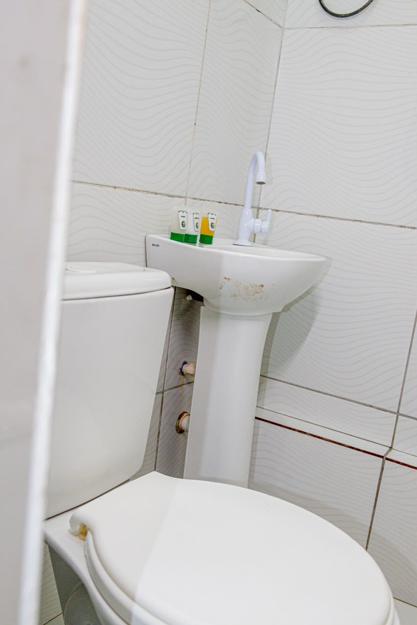 Une salle de bain équipée de toilettes, d’un lavabo et d’un porte-rouleau de papier toilette.