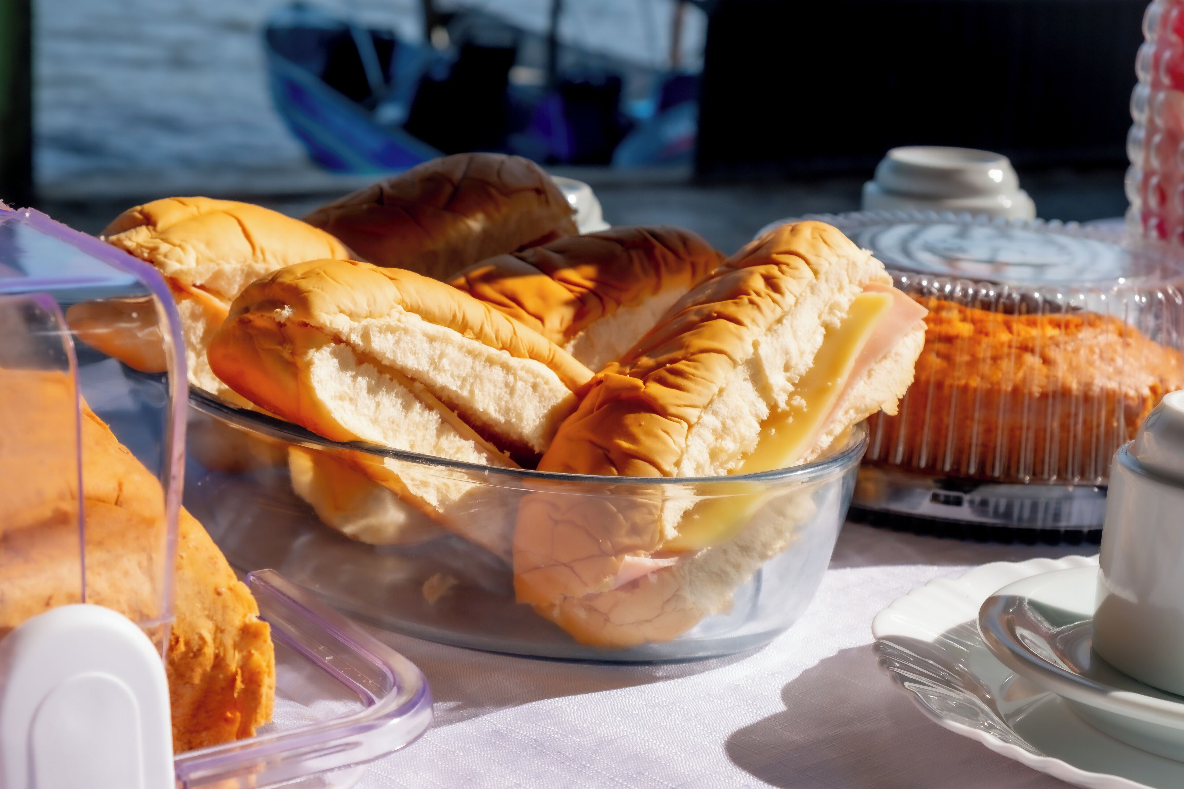 Una mesa con un bol de vidrio transparente que contiene sándwiches y un pastel.