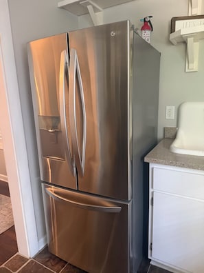 A stainless steel refrigerator with a freezer compartment, a water dispenser, and a built-in ice maker. - Clark Retreats (Atlanta)