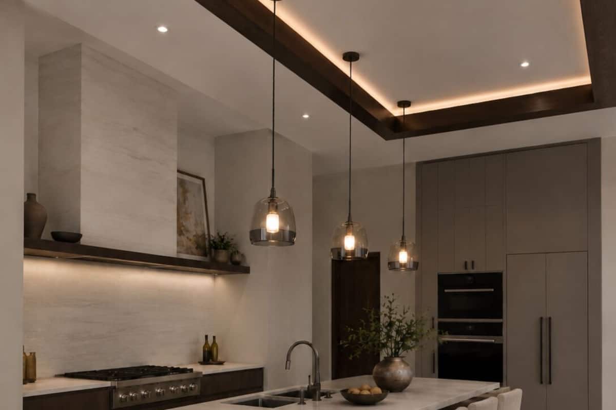 Una cocina moderna con una isla central, taburetes de bar, iluminación colgante y electrodomésticos integrados.