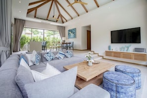 Una sala de estar moderna con un sofá grande, una mesa de centro y un televisor.