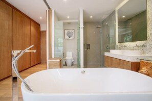 A modern bathroom with a large bathtub, a glass-enclosed shower, and a vanity with a mirror. - Trichada Villa 4 Luxury Residences (Thalang)