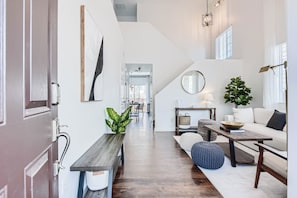 Een modern interieur met een houten bankje, een ronde spiegel, een potplant en een bank.