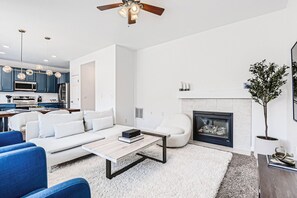 Un salon moderne avec un canapé, une table basse et une cheminée.