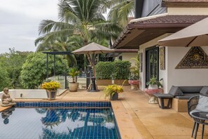 A swimming pool with tiled flooring, surrounded by potted plants and outdoor furniture. - Maan Tawan front beach Villa 12 (Choeng Thale)