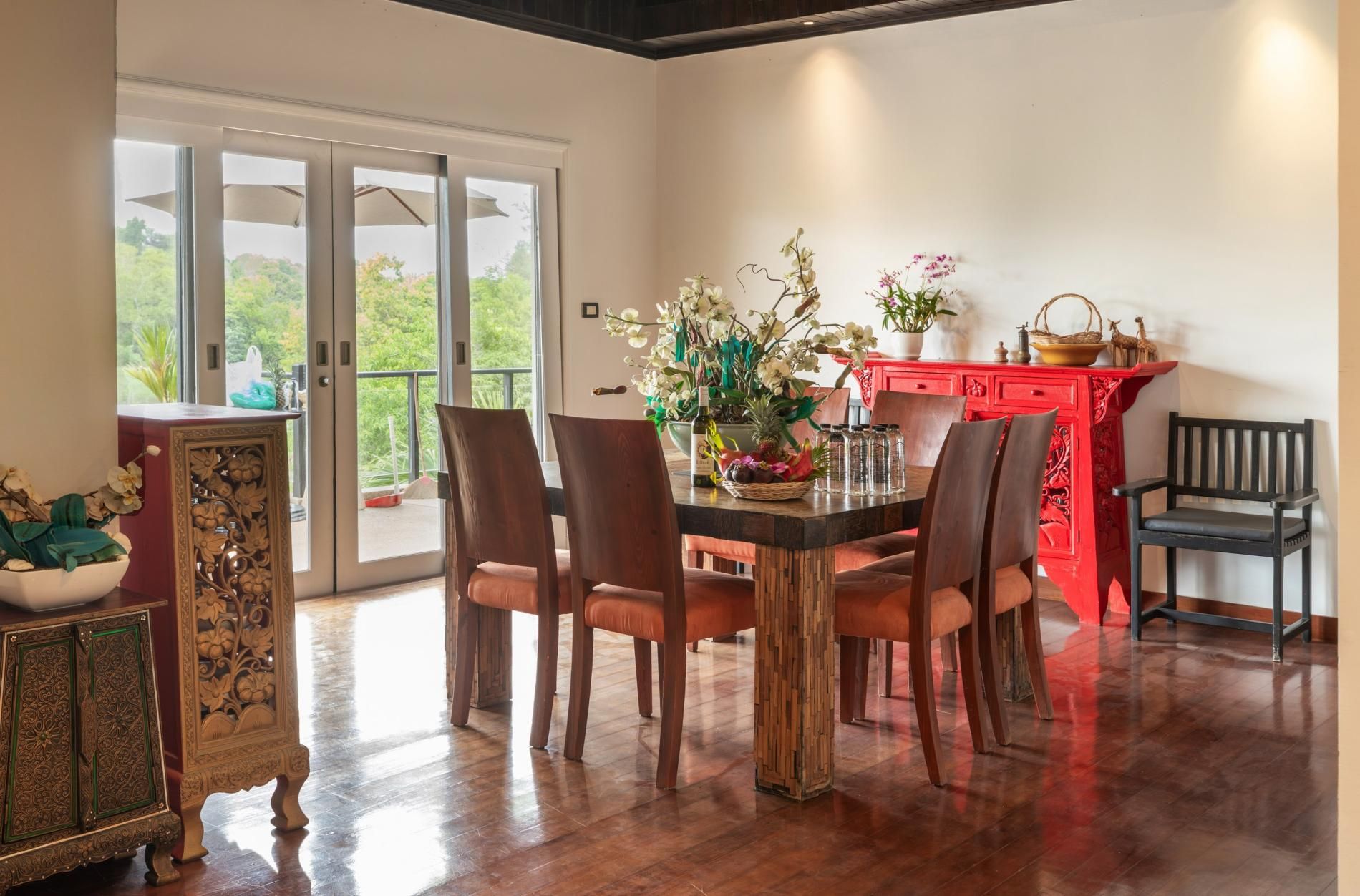 Un coin repas avec une table en bois, des chaises et un buffet rouge agrémenté d’objets décoratifs.