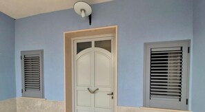 Ein Zimmer mit einer weißen Tür, zwei Fensterläden und einer Deckenleuchte.